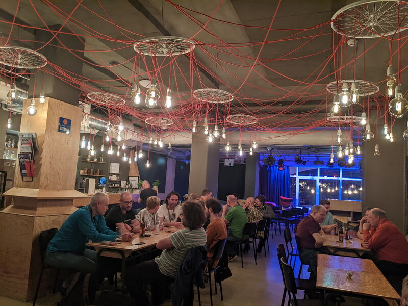 Blick über die Tische im Degginger Café am Abend, rote Kabel und Glühbirnen unter der Decke