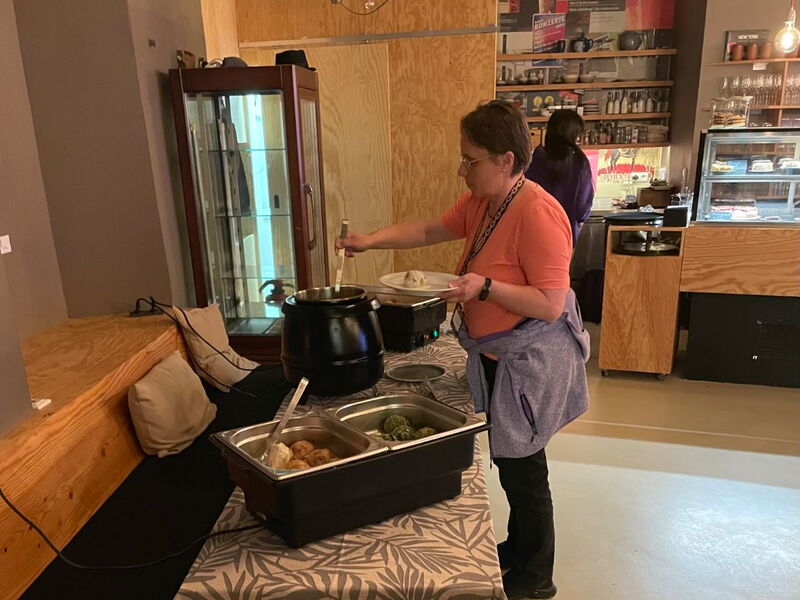 Eine Frau schöpft Essen aus einem Topf am Buffet