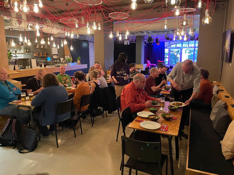 Volles Degginger Café mit Glühbirnen unter der Decke, Leute essen an langen Tischen