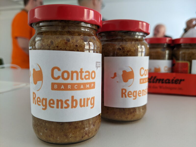 Senfgläser mit dem Etikett „Contao Barcamp Regensburg“ auf dem Tisch